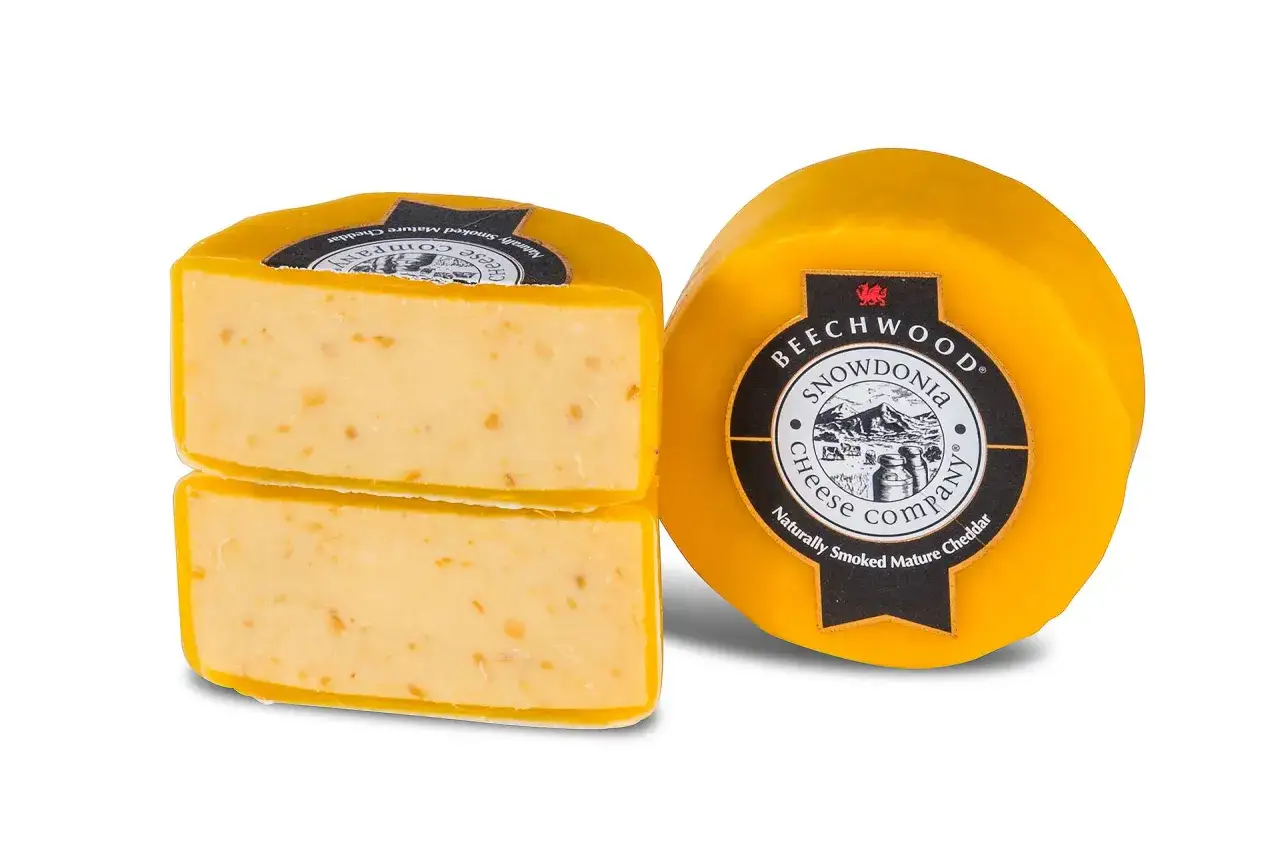 Zwei runde Käselaibe, einer angeschnitten, zeigen den hellgelben, reifen Cheddar. Perfekt für alle, die laktosearmen Genuss lieben.