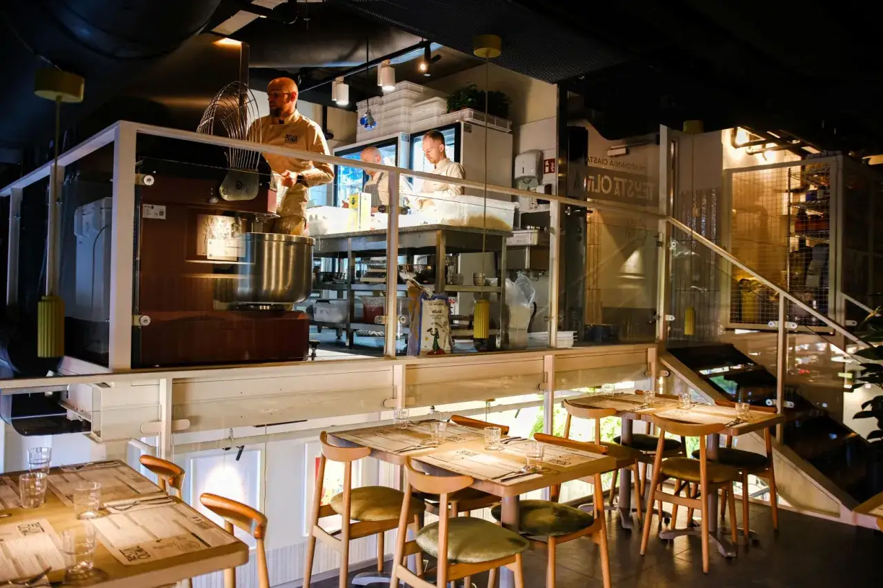 Nowe restauracje w Łodzi: kuchnia otwarta, gdzie widać pracę kucharzy przy wielkiej mikserze. Stoliki gotowe na gości.