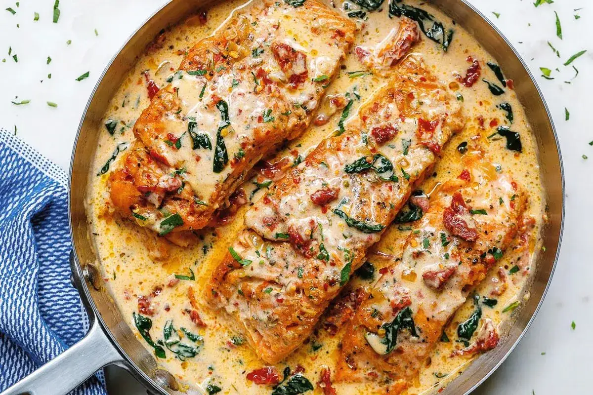 Trois pavés de saumon onctueux baignent dans une sauce crémeuse aux tomates séchées et épinards, un délice de saumon à la toscane.