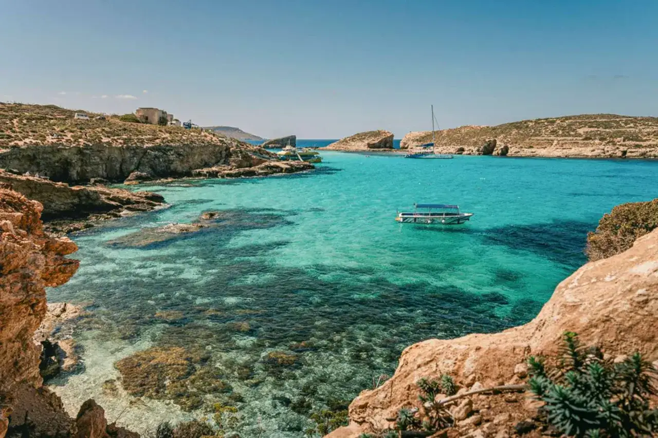 Malta plaże: turkusowa woda, skaliste wybrzeże i łodzie unoszące się na falach. Idealne miejsce na relaks.