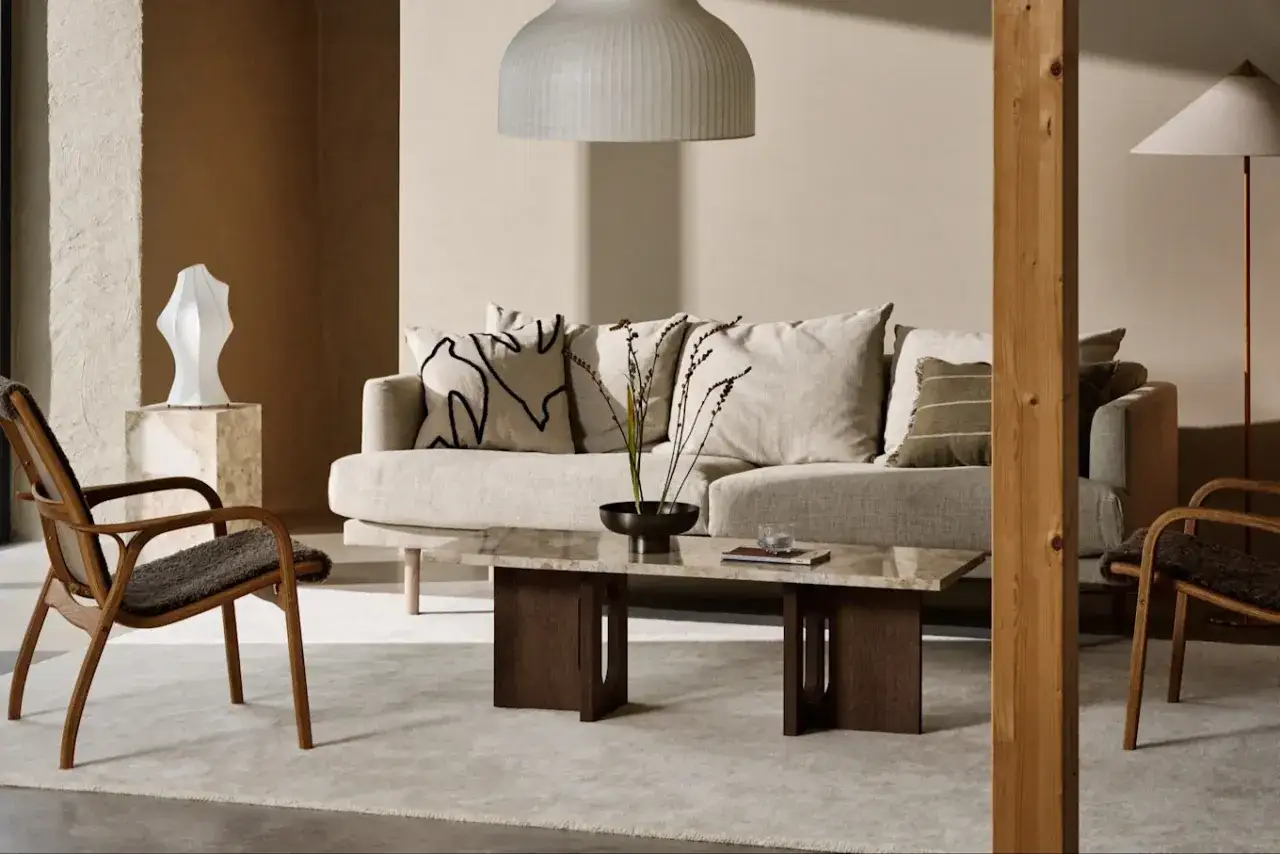 Vardagsrum med soffa, fåtöljer och marmorbord. En dansk designer har skapat en lugn och harmonisk atmosfär med naturliga material.