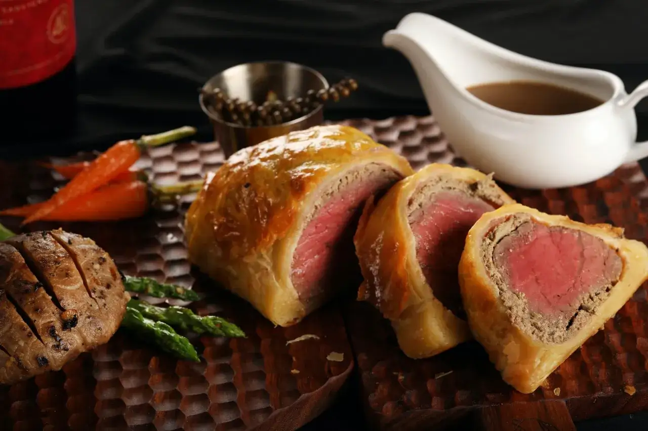 Wykwintne danie kuchni brytyjskiej: Beef Wellington z soczystym mięsem, podane z pieczonymi warzywami i sosem.
