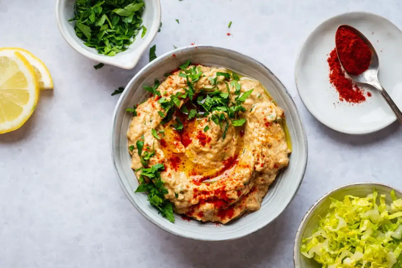 En krämig baba ganoush toppad med persilja och paprika, serverad med citronklyftor och sallad.