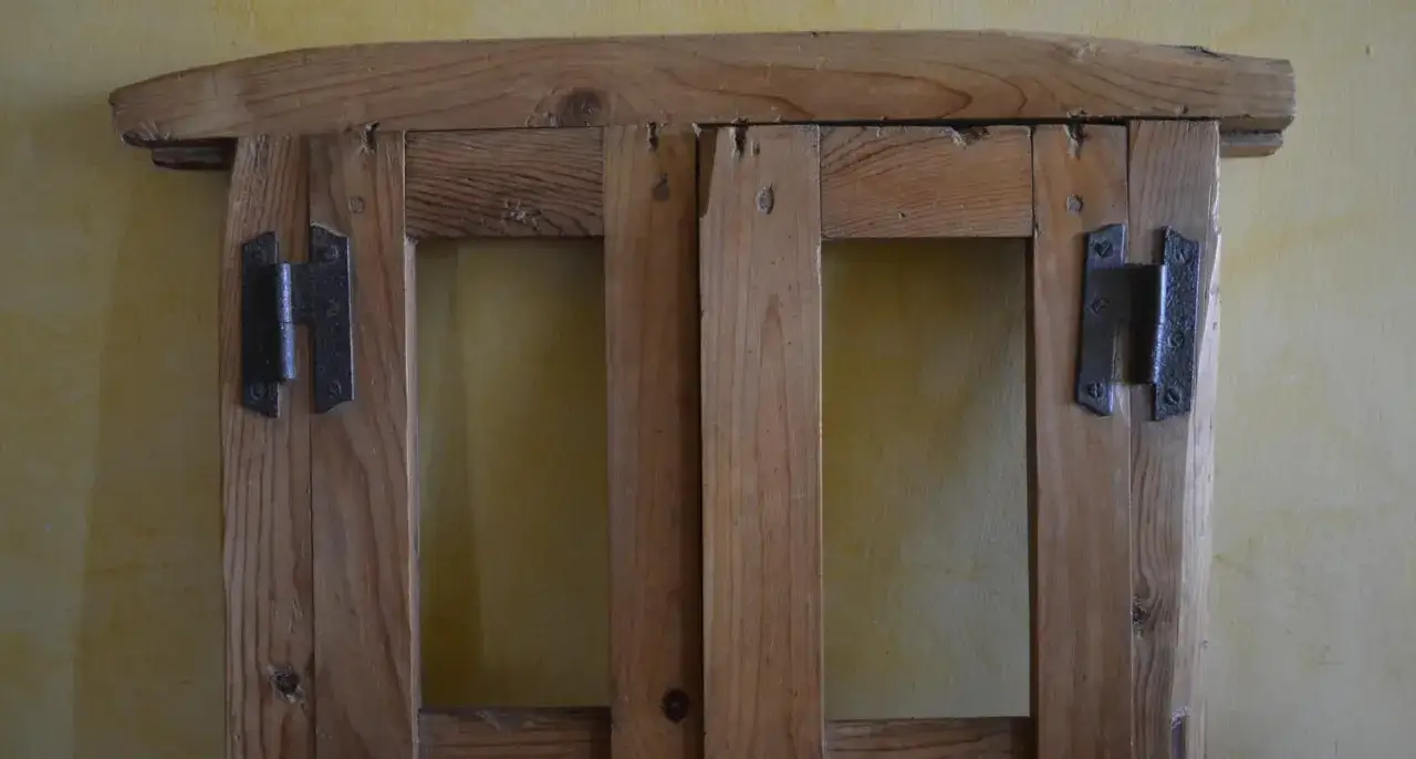 Marco de madera con dos puertas y bisagras met&aacute;licas, listo para restaurar ventanas de madera.