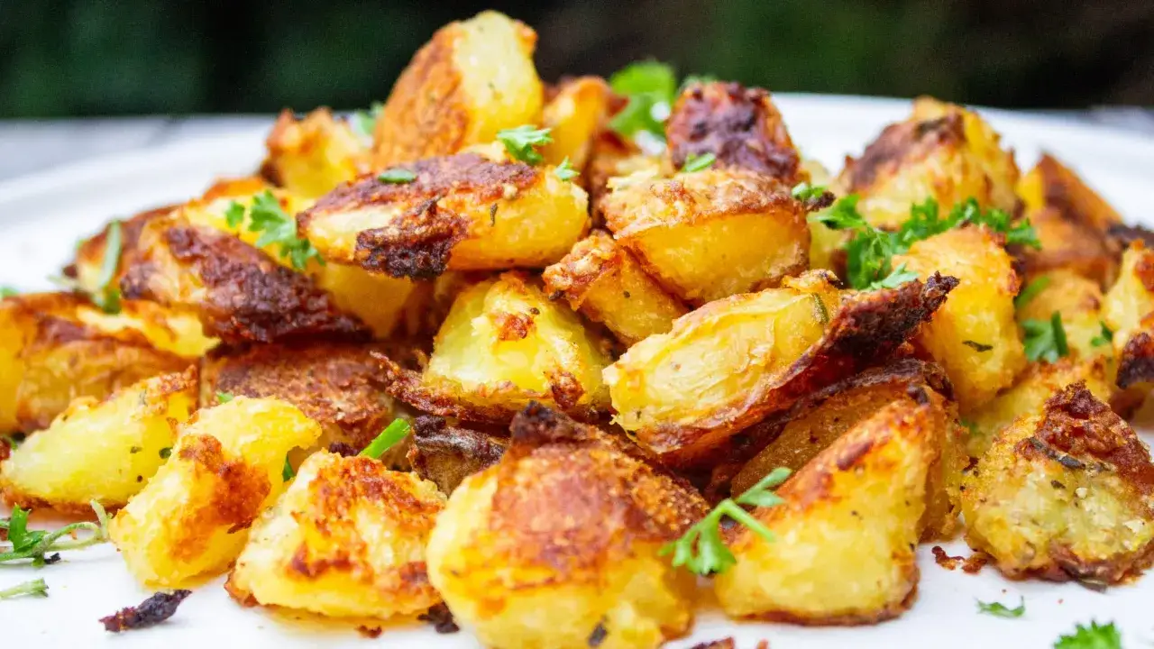En hög med gyllene, krispiga bakad potatis, toppad med färsk persilja. Perfekt tillbehör till middagen.