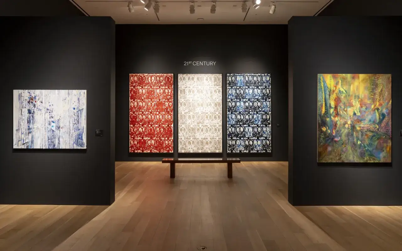 A gallery showcases abstract art, prompting the question: is investing in art a good idea? The pieces range from a white and blue abstract to three patterned works and a vibrant, colorful painting.