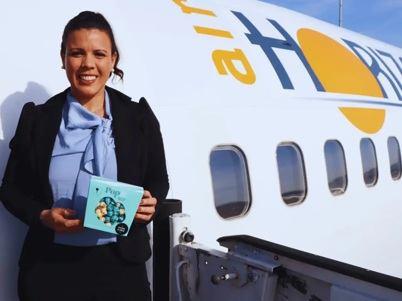 Mujer sonríe junto a un avión con logo