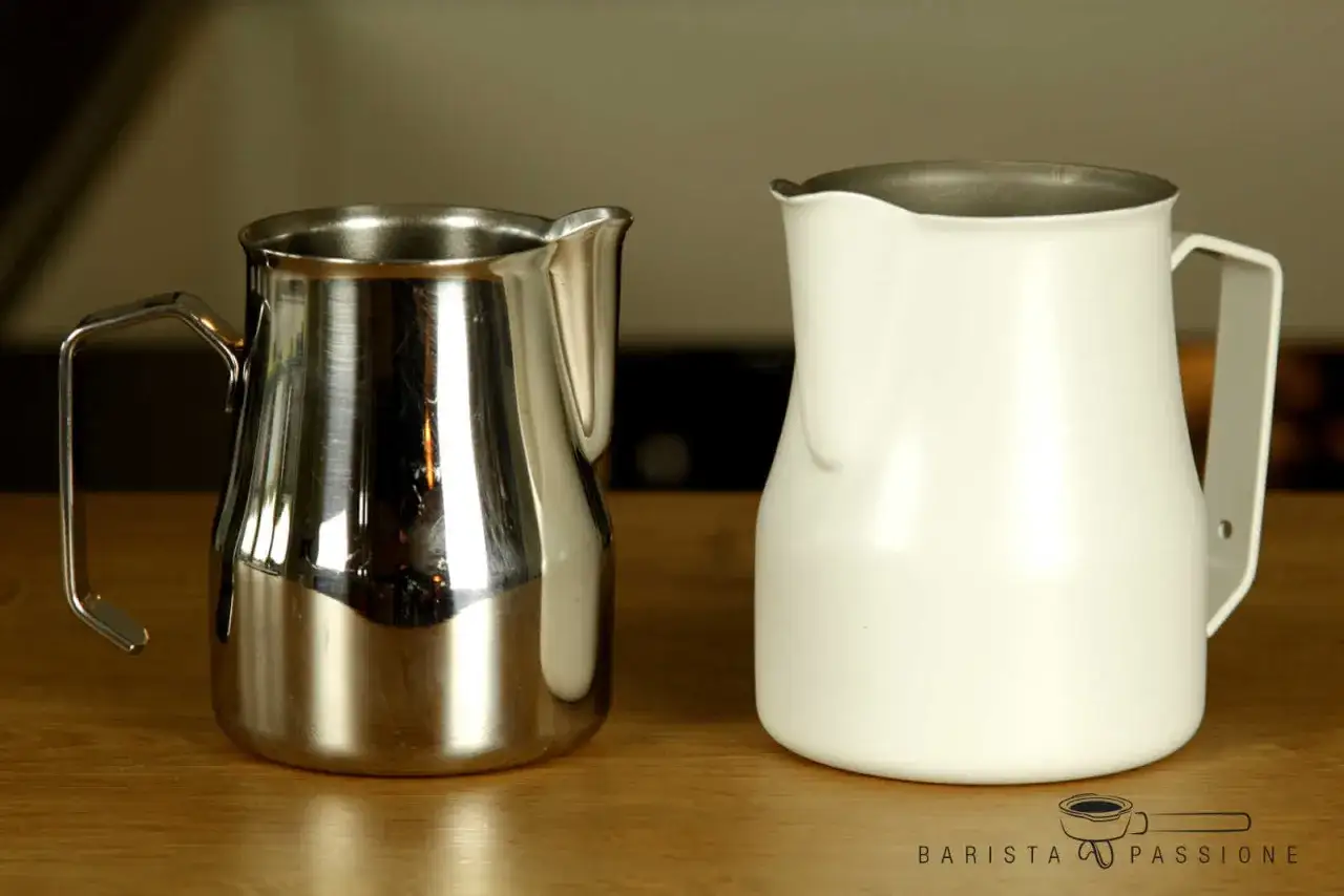 Zwei Milchkännchen, eines aus glänzendem Edelstahl, das andere weiß, bereit für perfekten Kaffee-Schaum.