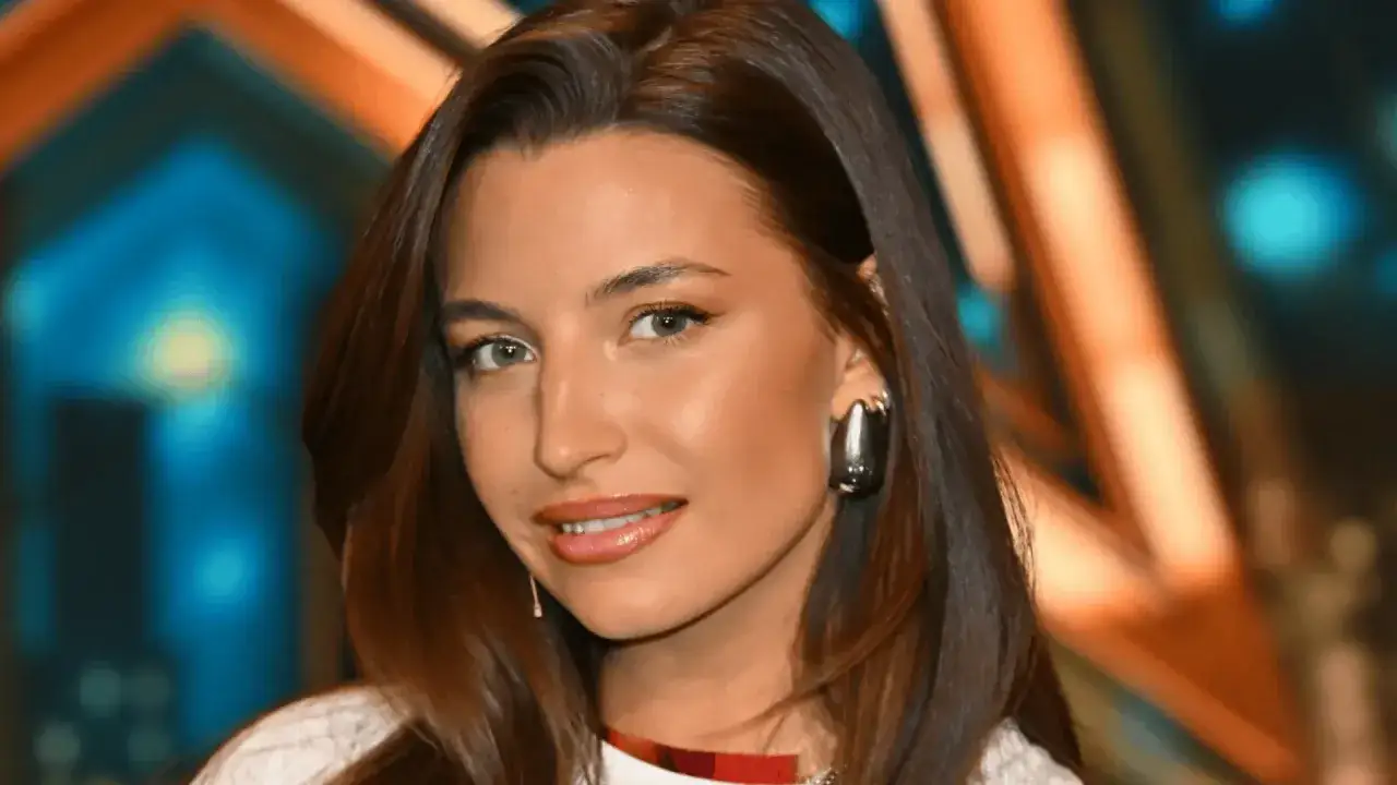 Uśmiechnięta Julia Wieniawa, ciekawa ile lat ma, w błyszczącej stylizacji.