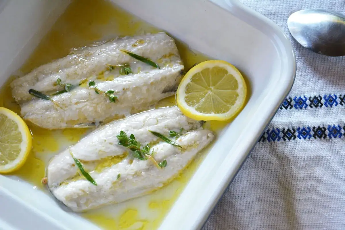 Deux filets de maquereau au four, napp&eacute;s d'une sauce dor&eacute;e, orn&eacute;s de rondelles de citron et de brins de thym frais.