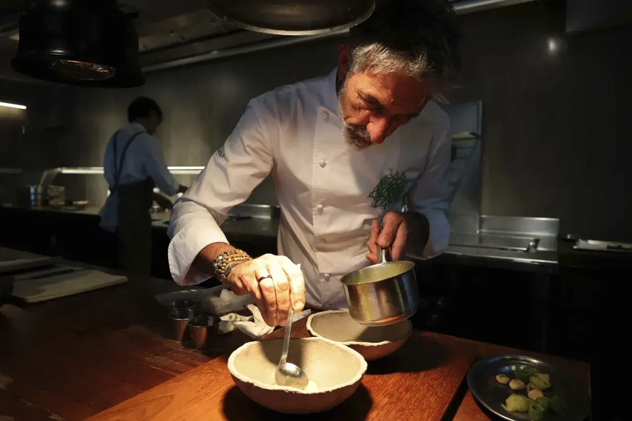 Chef con 5 estrellas Michelin prepara un plato con delicadeza en una cocina profesional.