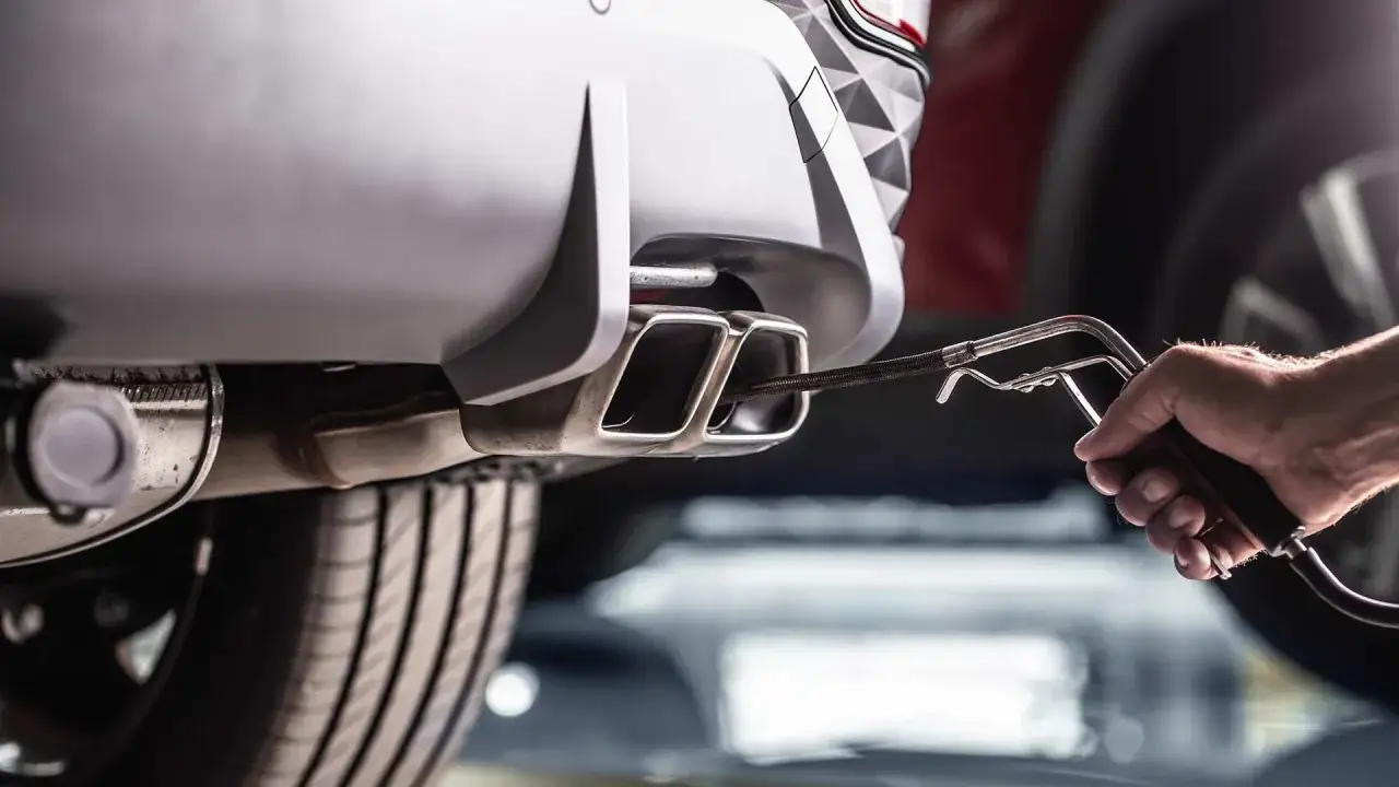 Messung des Kraftstoffverbrauchs am Auspuff eines Autos. Ein Werkzeug wird in die Doppelrohre eingeführt.
