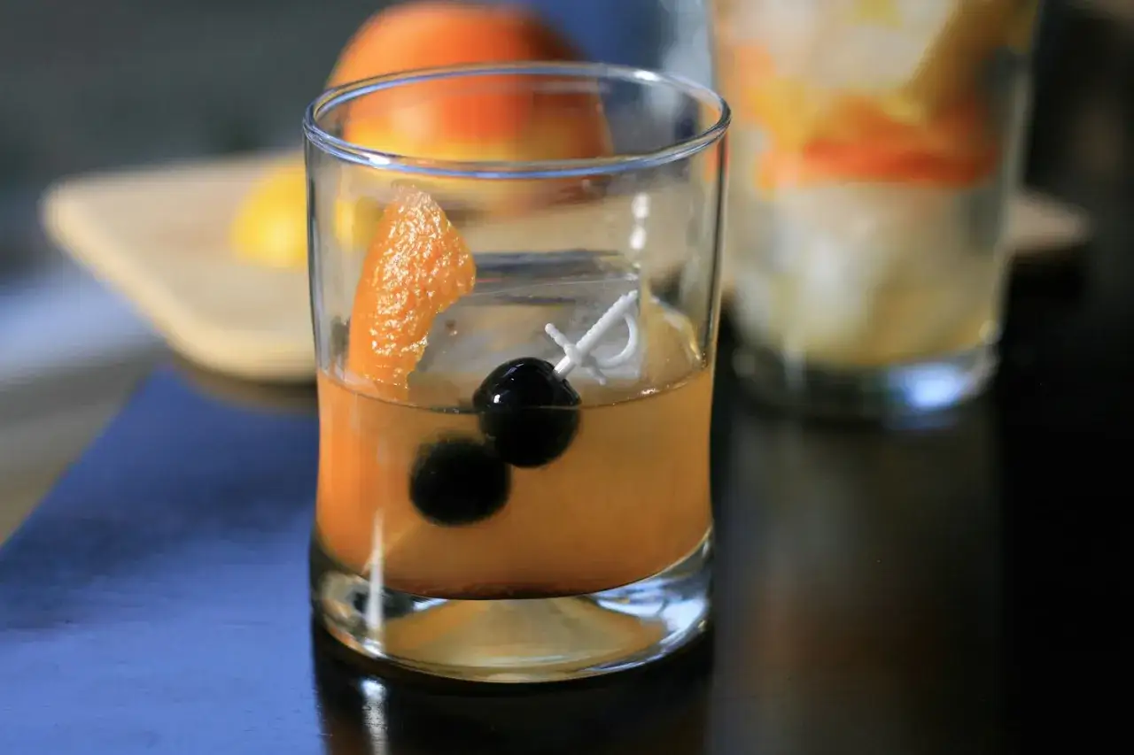 Ein Old Fashioned mit Irish Whiskey, garniert mit Orangenschale und Kirschen. Ein klassischer Drink, der perfekt zu jeder Gelegenheit passt.