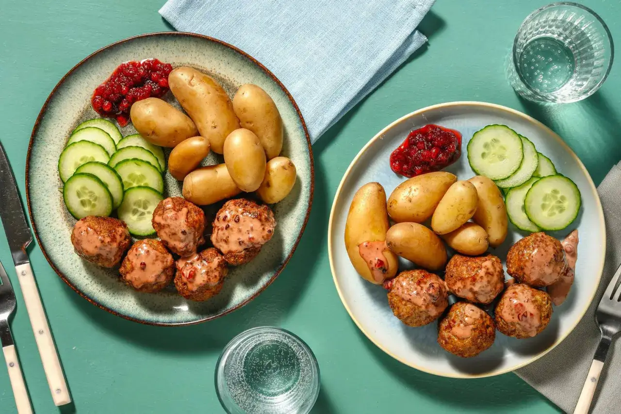 Två tallrikar med köttbullar, småpotatis, gurka och lingonsylt. Ett klassiskt potatis recept som passar alla.
