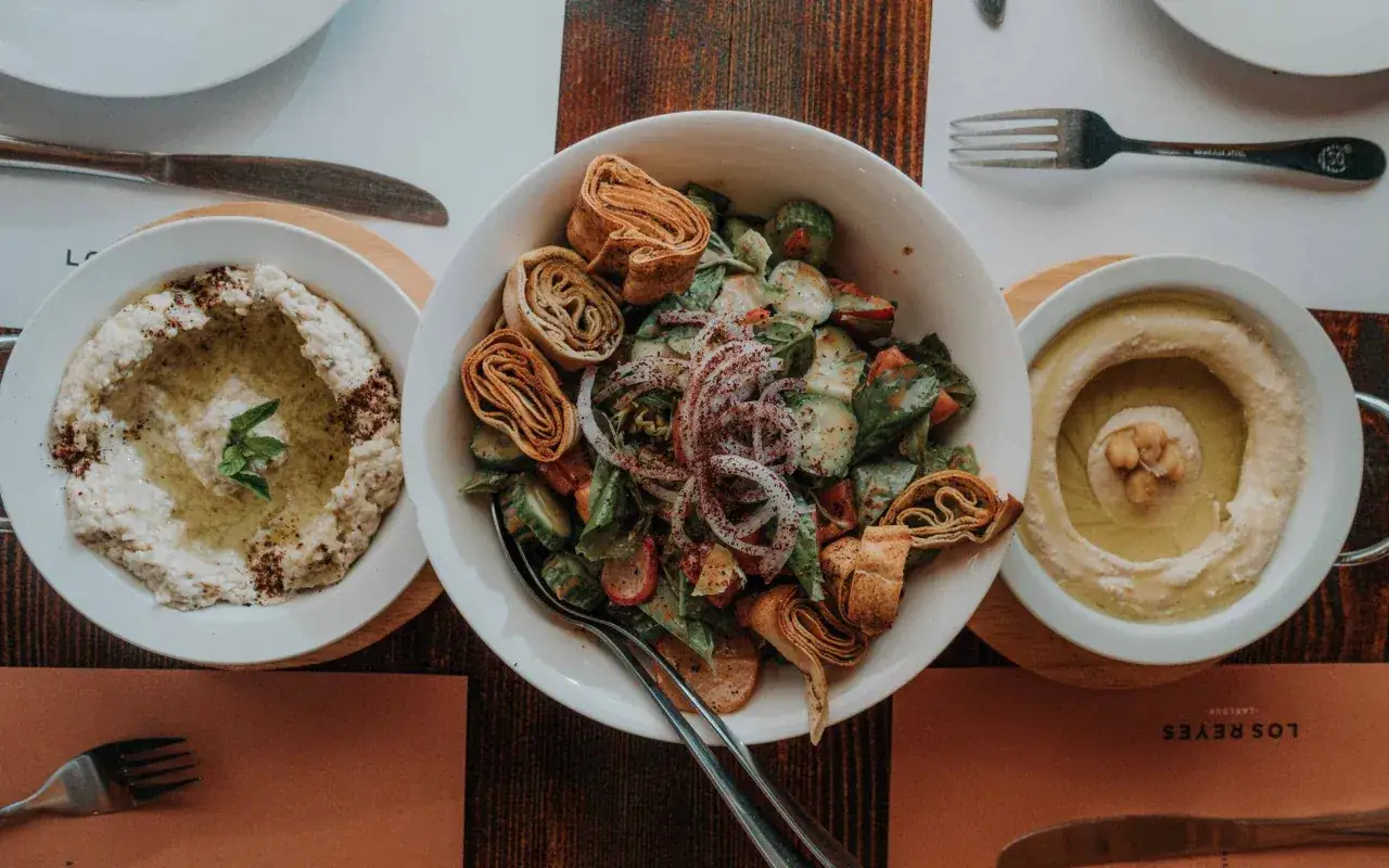 Pyszne dania kuchni libańskiej: kremowe hummus, baba ghanoush i świeża sałatka fattoush z chrupiącymi kawałkami pity.