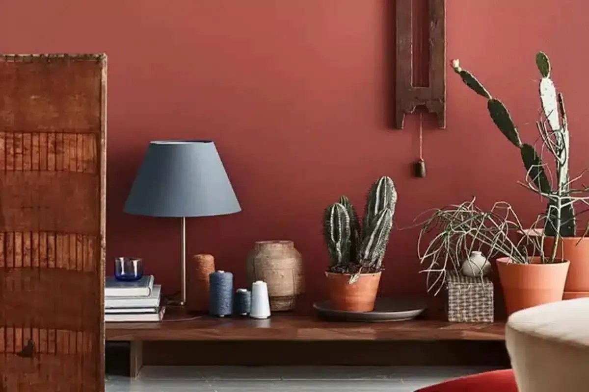 Un angolo accogliente con lampada, piante grasse e filati, che riflette le attuali tendenze arredamento.