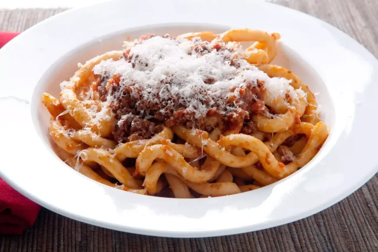 Pici al ragù, un classico da provare per capire cosa mangiare a Siena. Pasta fatta a mano con sugo di carne e abbondante parmigiano.