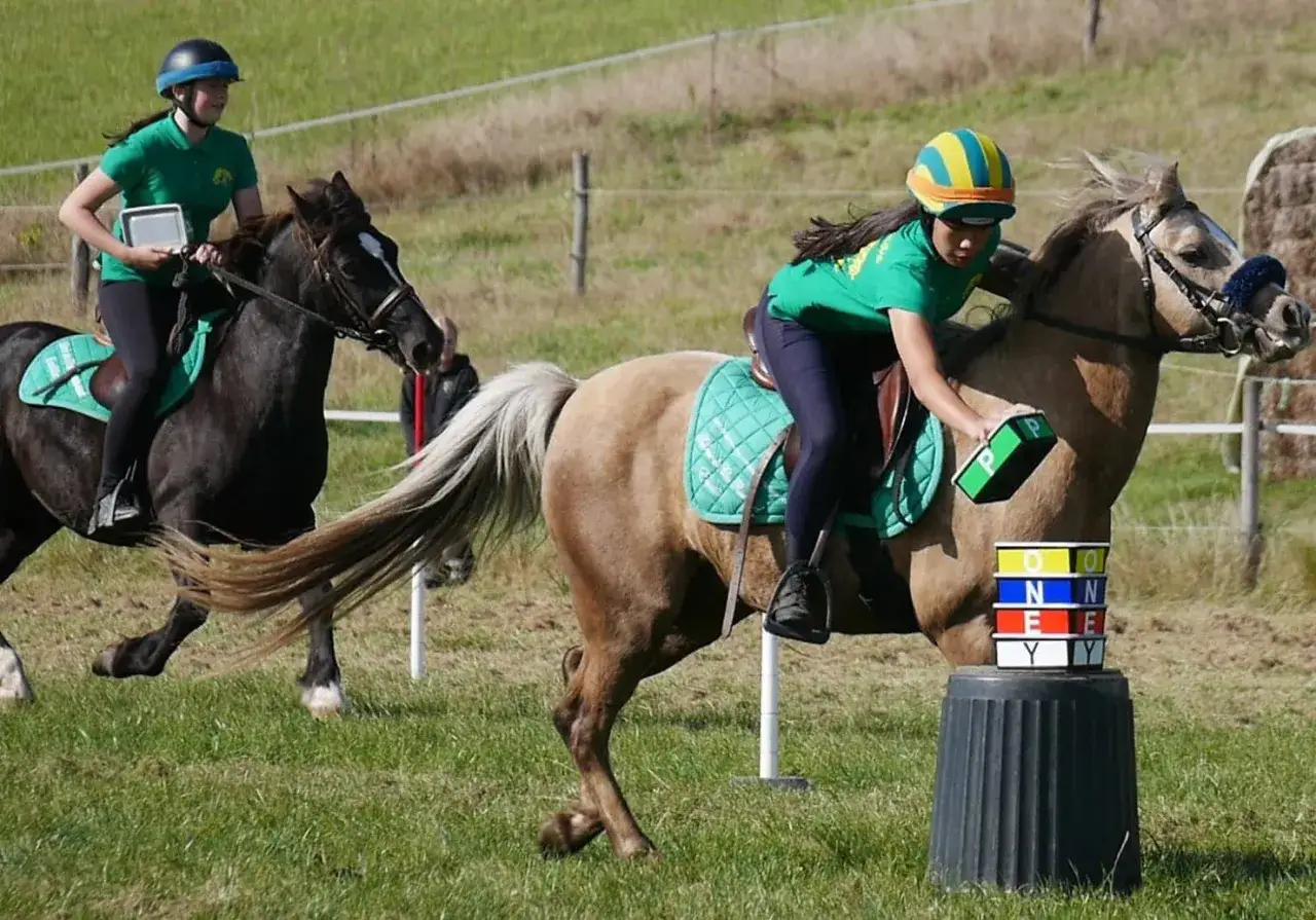 Deux jeunes cavalières en action, prouvant que l'équitation est un sport exigeant. Elles manœuvrent leurs poneys lors d'une épreuve.