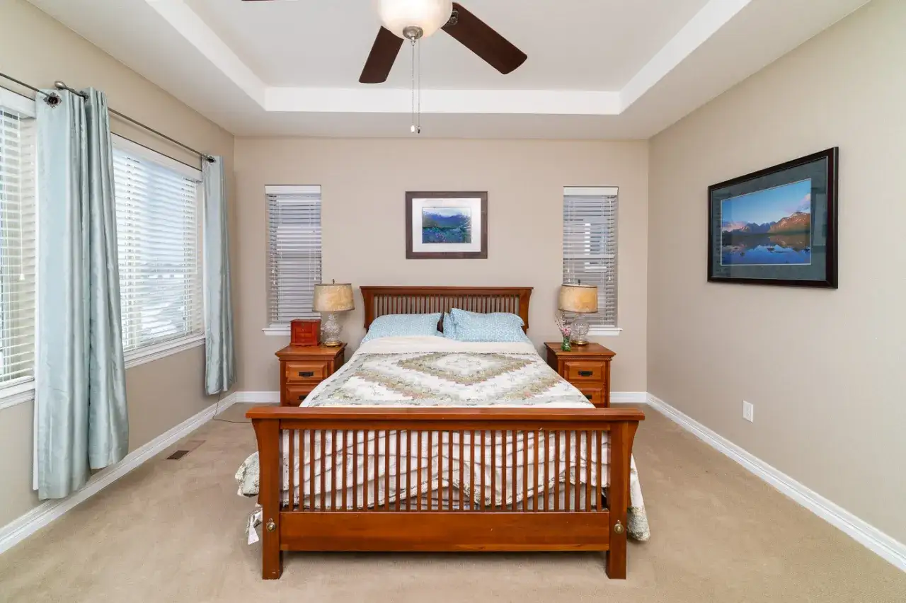 Masterful real estate photography lighting showcases a serene bedroom with a wooden bed, soft curtains, and warm bedside lamps.
