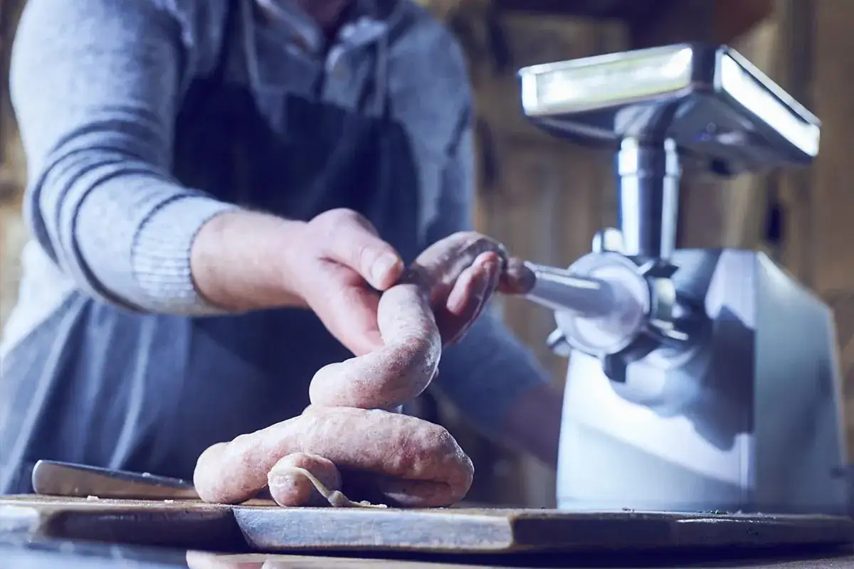 Mann macht Bratwurst selber mit einem Fleischwolf. Ein tolles Rezept f&uuml;r frische Wurst.