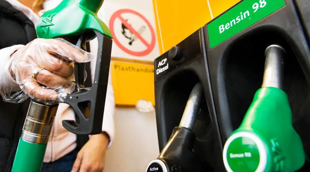 En person med plasthandske håller i en pump för bensin 98. Bredvid finns en pump för diesel.