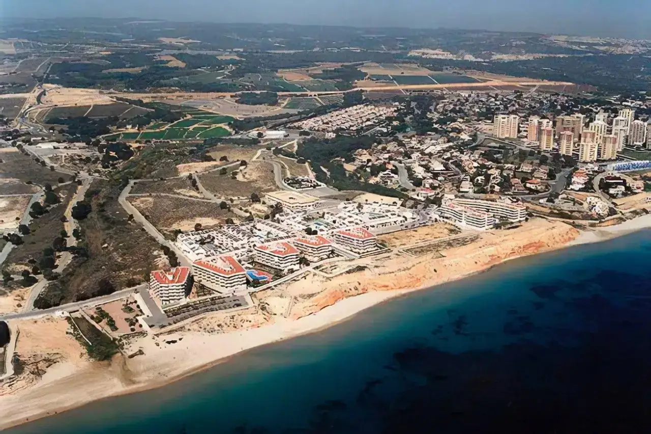 Vista aérea de una **playa de mil palmeras** con complejos residenciales modernos y el mar azul.