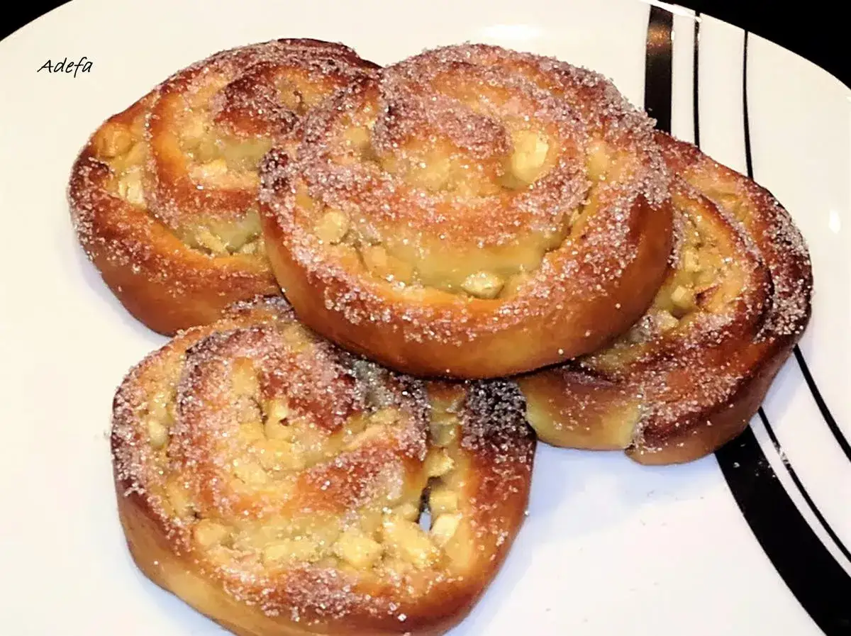 Vier goldbraune Apfelschnecken mit Zucker bestreut, bereit zum Genießen. Ein köstliches Apfelschnecken Rezept.