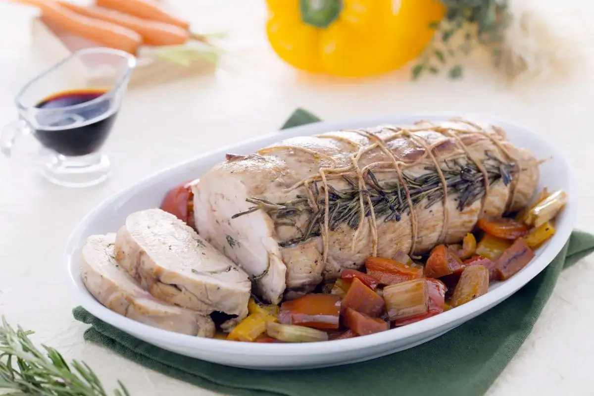 Jugoso solomillo de pavo asado con hierbas, servido con pimientos y tomates.
