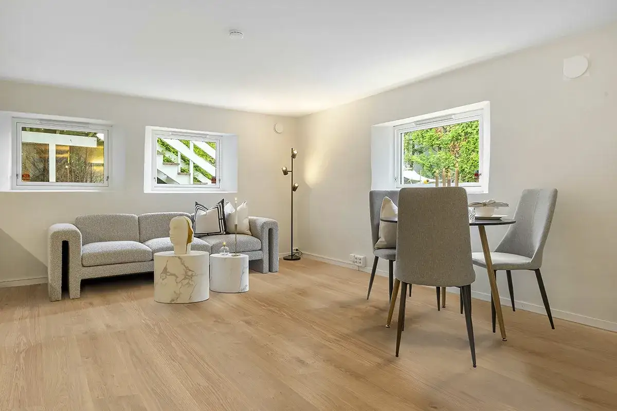 Soggiorno moderno con divano grigio, tavolini rotondi in marmo e zona pranzo. Una casa minimalista che invita al relax.