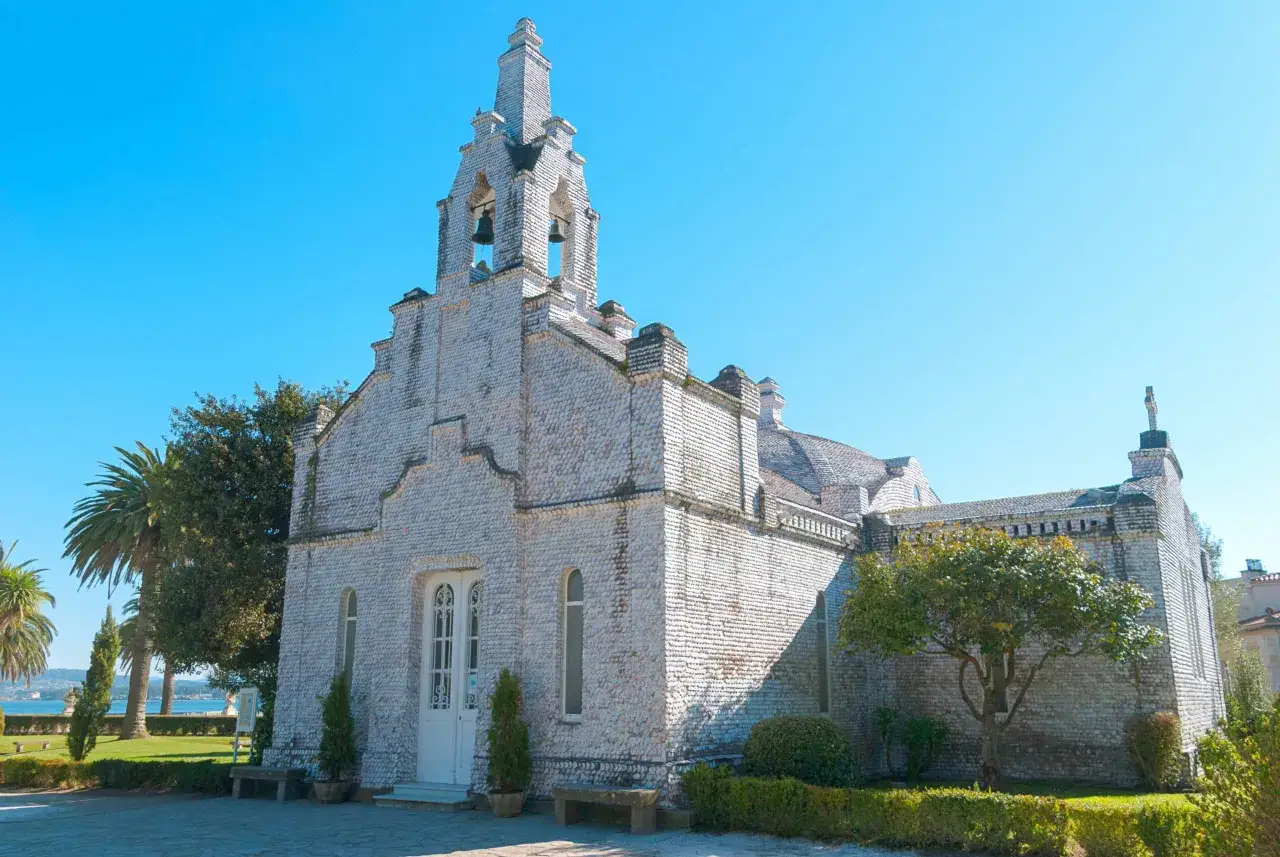 La iglesia de conchas en Galicia, un edificio único cubierto de miles de conchas marinas, se alza bajo un cielo azul.