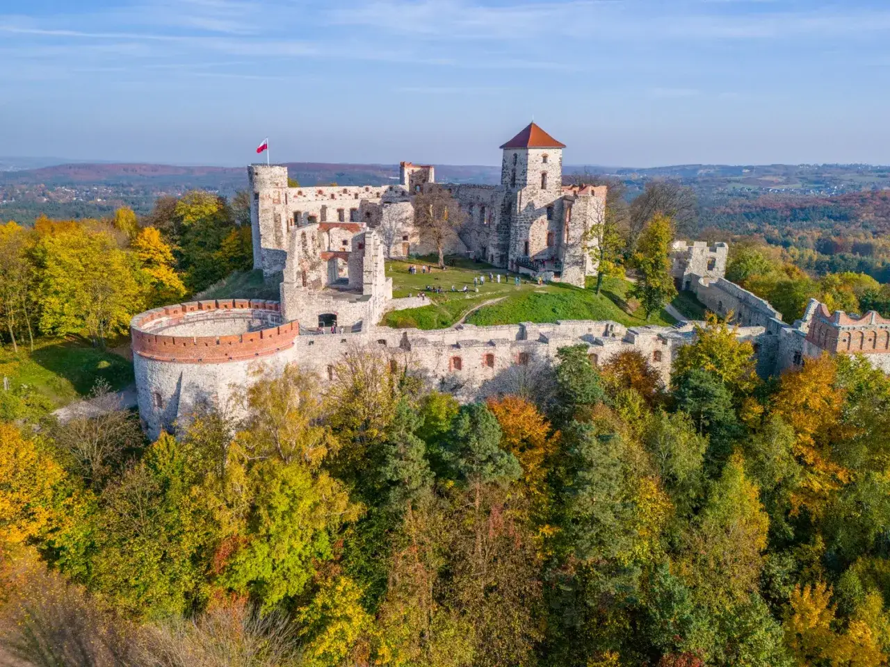 Ruiny zamku na Szlaku Orlich Gniazd otoczone jesiennymi drzewami.