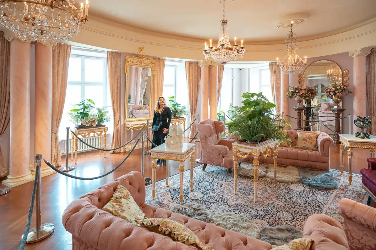 Elegancki salon z różowymi sofami i kryształowymi żyrandolami. Marzenie o noclegu w zamku staje się rzeczywistością w tym luksusowym wnętrzu.