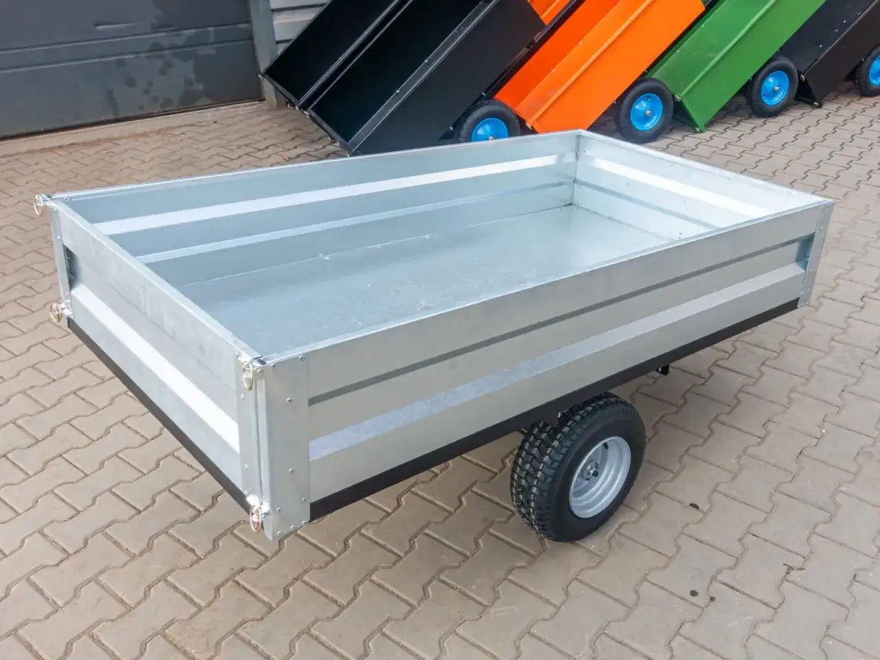 Solidna, galwanizowana przyczepka do traktorka, gotowa do transportu ziemi, liści czy narzędzi.