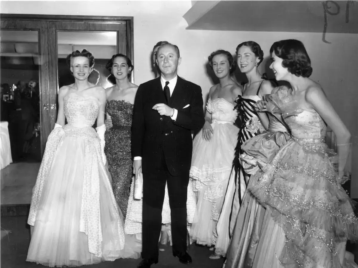 Eleganza senza tempo: un uomo con un abito scuro e cinque donne in abiti da sera da sogno, un vero new look Dior anni '50.