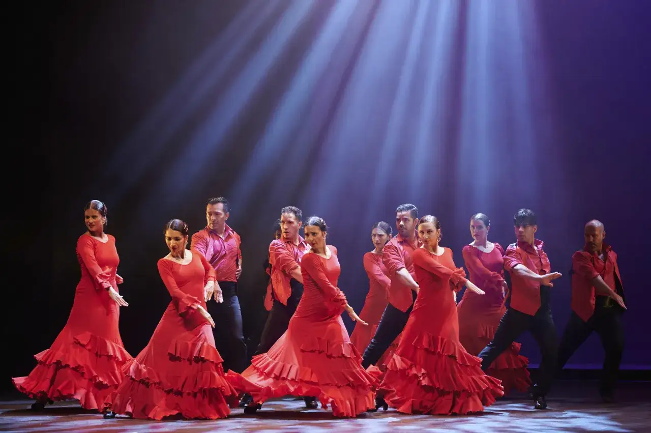 Tancerze w czerwonych strojach wykonują pełen pasji taniec flamenco.