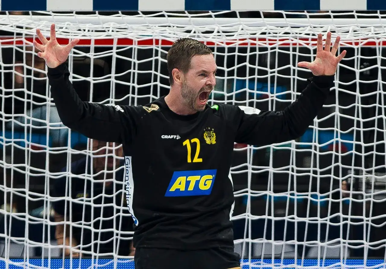 Bramkarz Andreas Palicka w akcji, z rękami uniesionymi w geście triumfu lub frustracji, na tle siatki bramki.