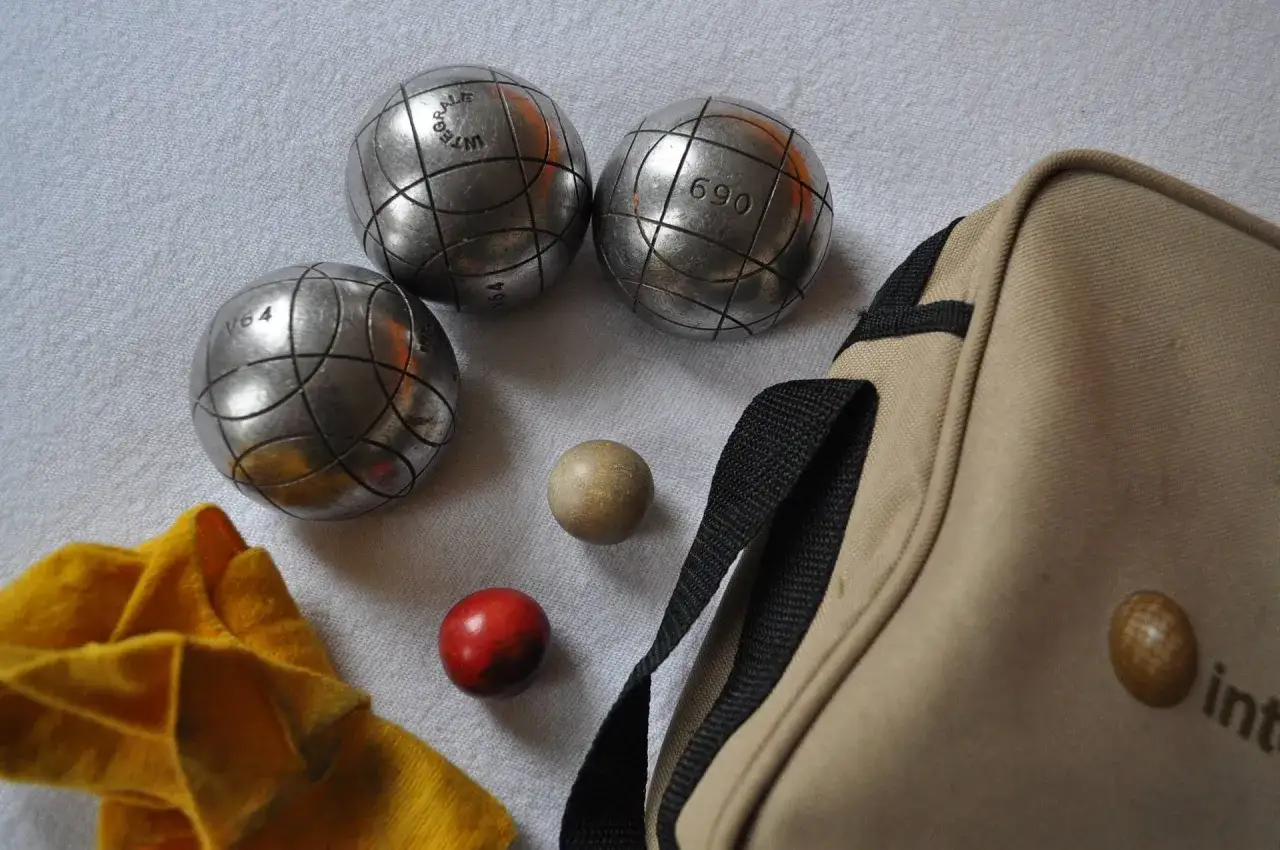 Trois boules de p&eacute;tanque m&eacute;talliques, une petite boule en bois et une rouge, un tissu jaune et une sacoche beige. Que faire avec ces boules de p&eacute;tanque qui glissent ?