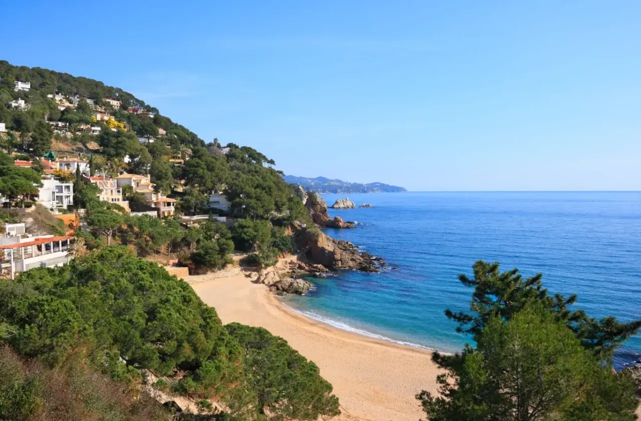 Piękna pogoda na Costa Brava: złota plaża, turkusowe morze i zielone wzg&oacute;rza z białymi domkami. Idealne miejsce na wakacje.