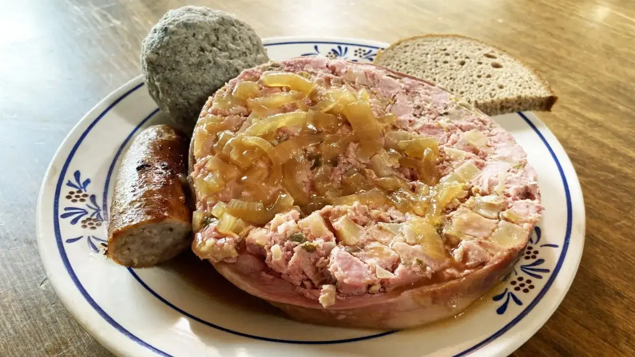 Saumagen-Rezept: Ein deftiger Saumagen mit Zwiebeln, dazu eine Bratwurst und Brot.