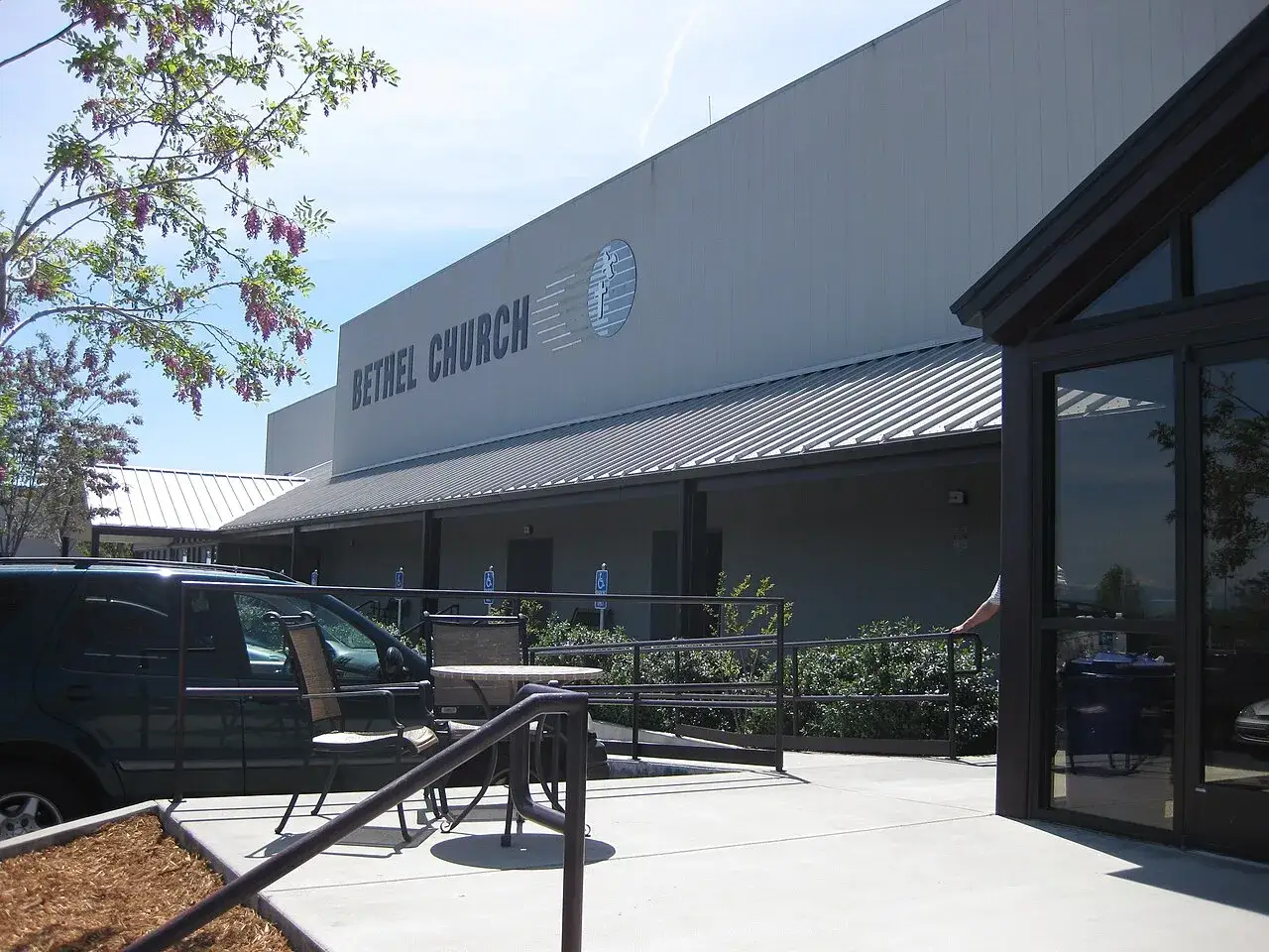 Bethel Church: Außenansicht eines modernen Gebäudes mit Parkplatz und Sitzbereich. Kritische Betrachtung der Architektur.