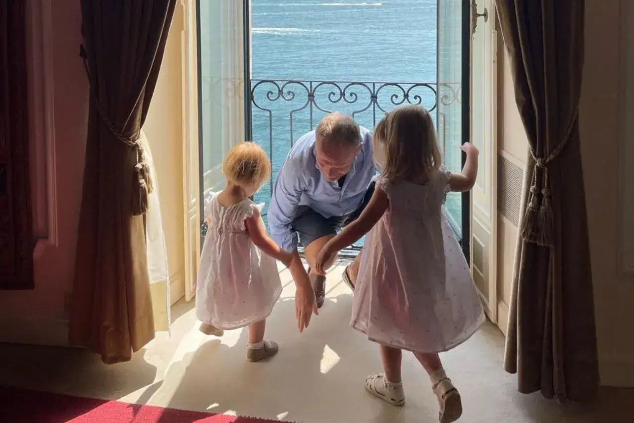 Donald Tusk z dwoma wnuczkami, które trzyma za ręce, patrzą na morze.