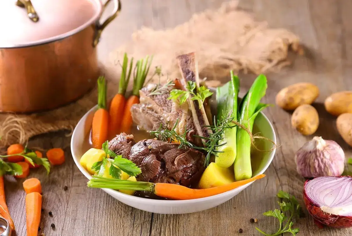 Un plat réconfortant de pot-au-feu, avec du bœuf, des carottes, des poireaux et des pommes de terre, prêt à être dégusté.