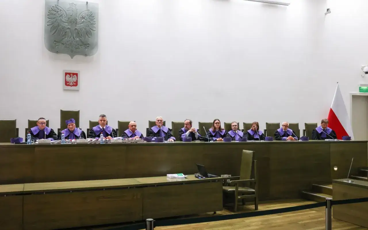 Sędziowie w togach siedzą za stołem w sali sądowej, obok flagi Polski. To ważny moment dla trybunału stanu.