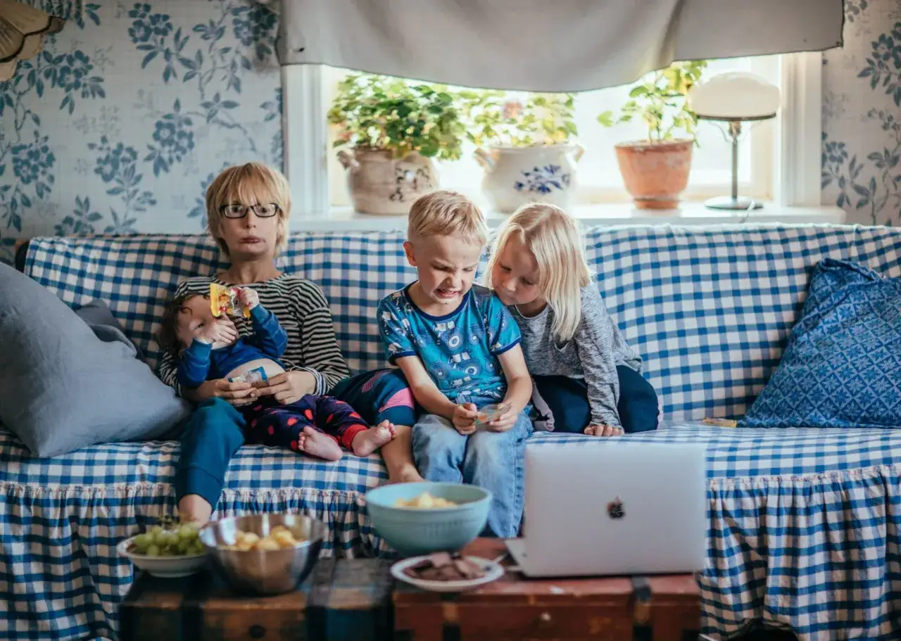 En familj myser i soffan med snacks och en film, perfekta fredagsmiddag tips f&ouml;r en lugn kv&auml;ll.