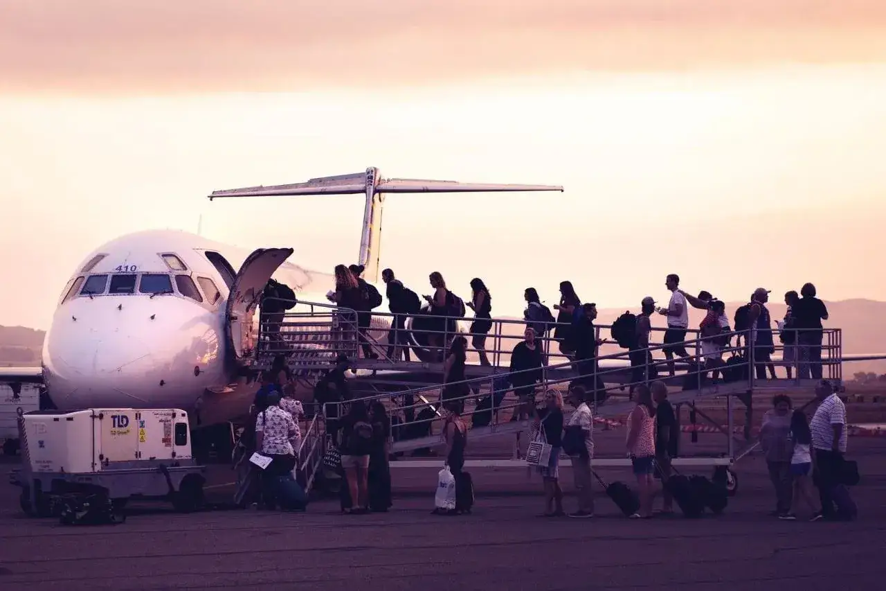 Tłum pasażerów wchodzi po schodkach do samolotu. Czy to przez overbooking Ryanair, że tyle osób?