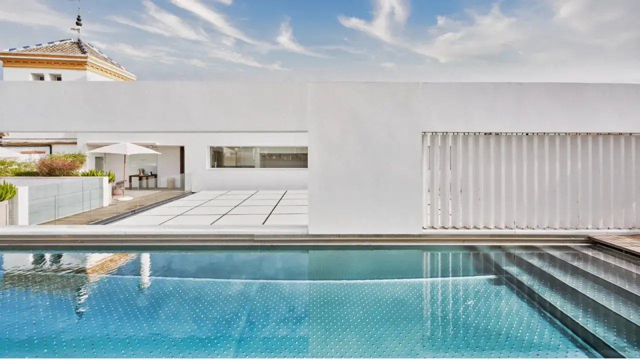 Piscina cristalina y terraza moderna en un hotel Radisson Collection. Cielo azul con nubes.