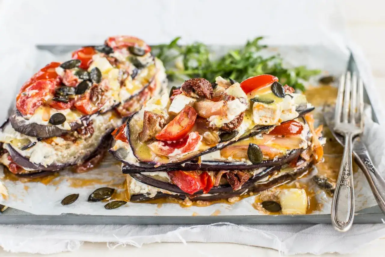 Gestapelte Auberginen-Schichten mit Tomaten, K&auml;se und K&uuml;rbiskernen. Ein einfaches Gericht, das Lust auf mehr macht.