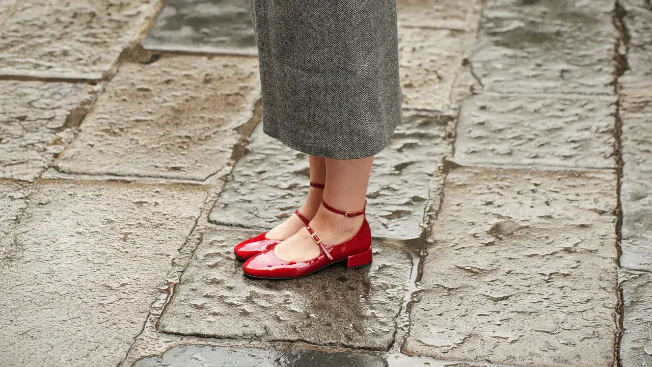 Scarpe rosse lucide con cinturino alla caviglia, perfette scarpe che slanciano la caviglia, su un selciato bagnato.