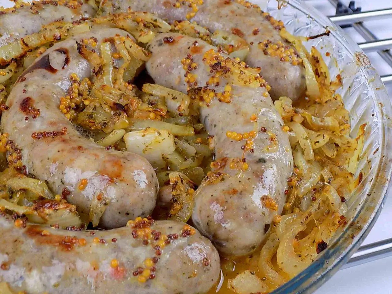 Pyszna biała kiełbasa pieczona z cebulką i musztardą w naczyniu żaroodpornym.