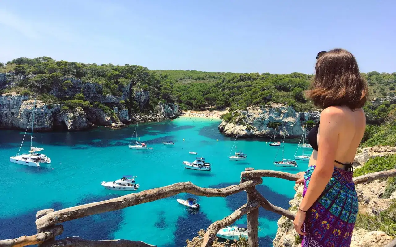 Traumhafte Bucht mit t&uuml;rkisfarbenem Wasser, Booten und einem Strand. Perfekt f&uuml;r Menorca Urlaub Tipps!